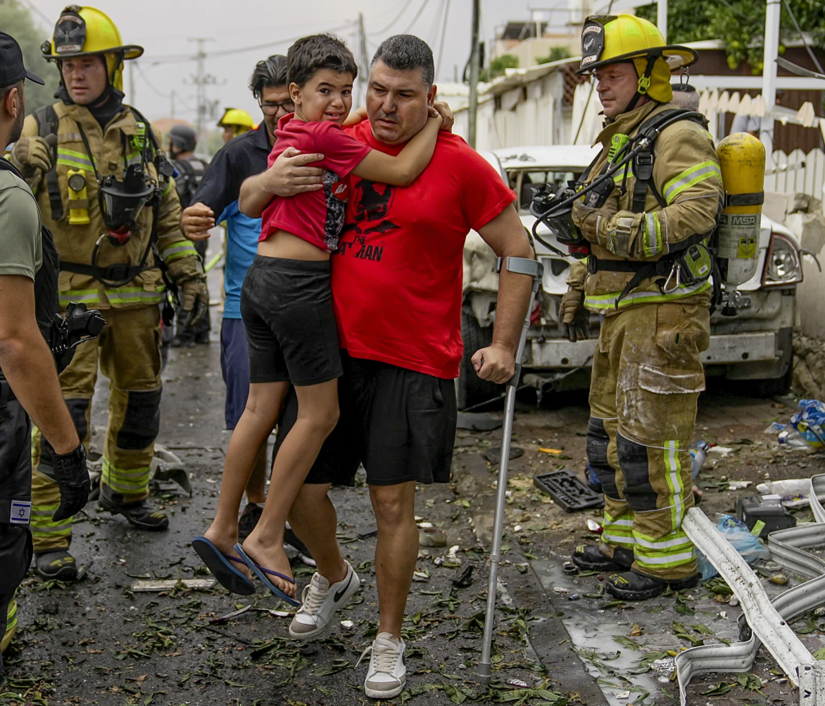 A father holding his injured son after a bombing attack.