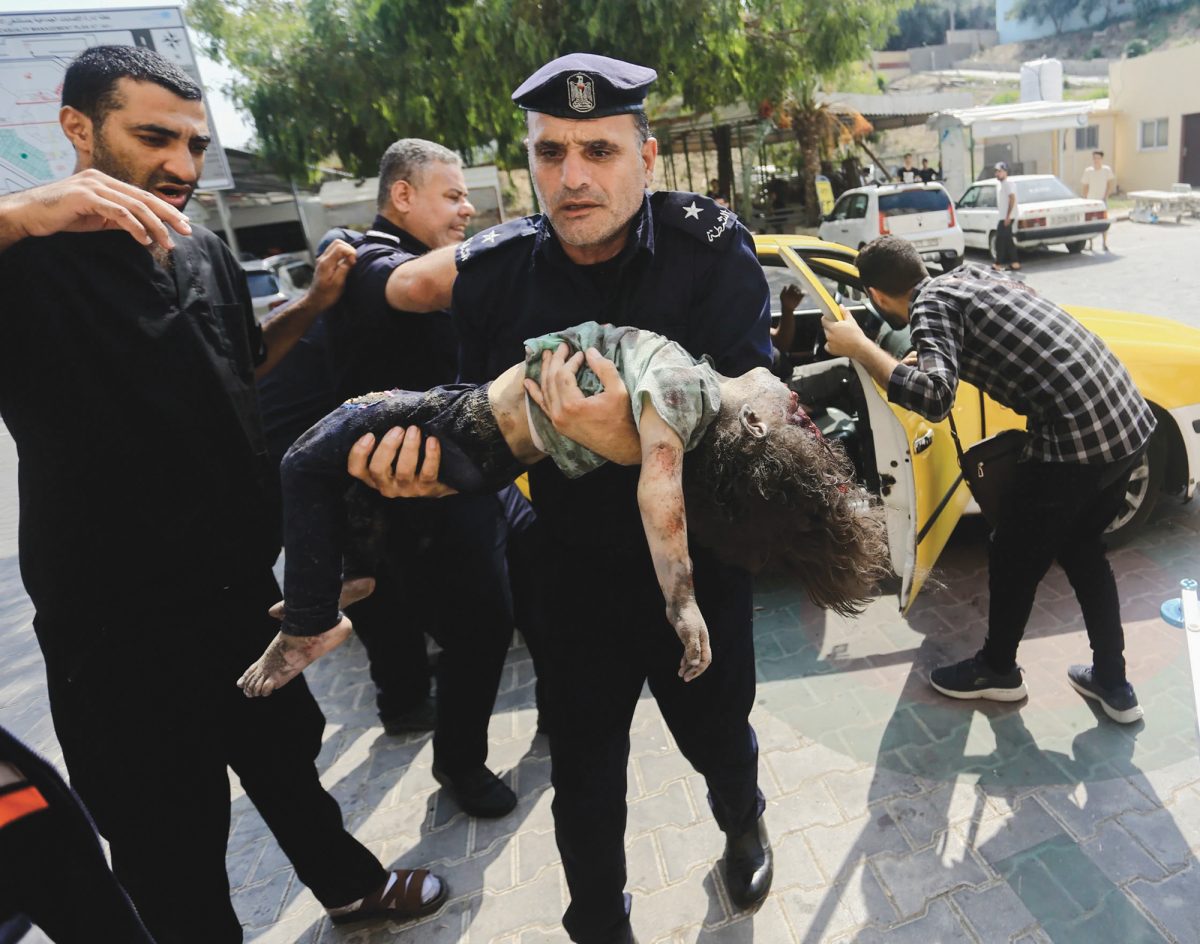 A Hamas police officer carries a wounded girl into a hospital in Beit Lahiya in the Gaza Strip early in the war.
