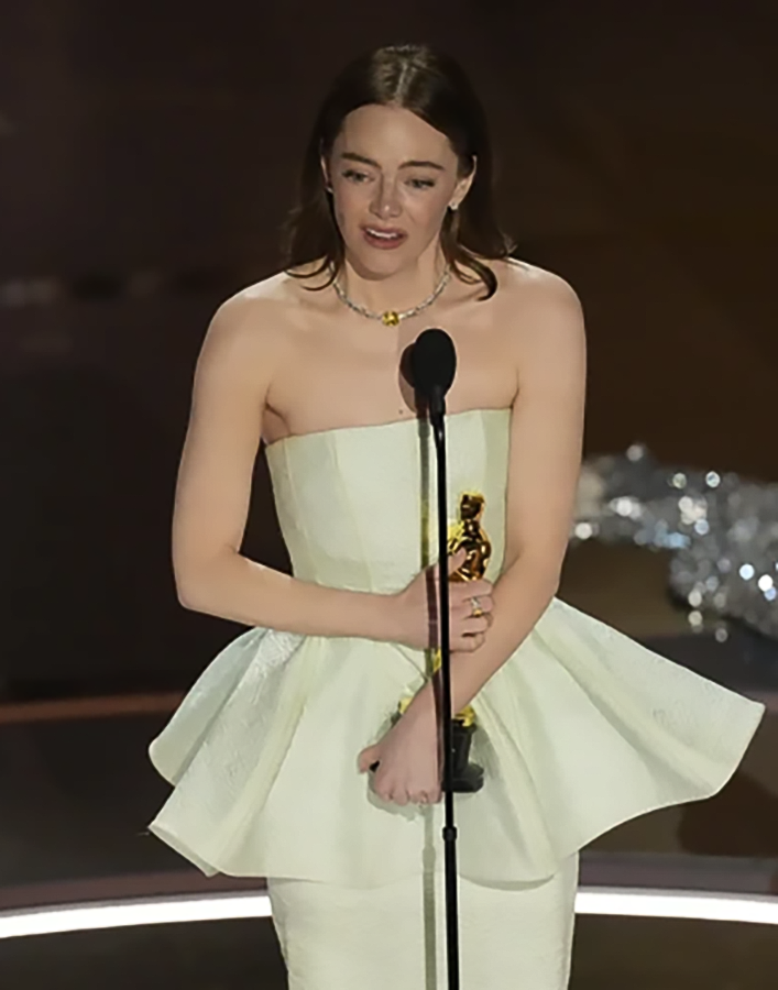 Emma Stone accepts the award for best performance by an actress in a leading role for “Poor Things.”