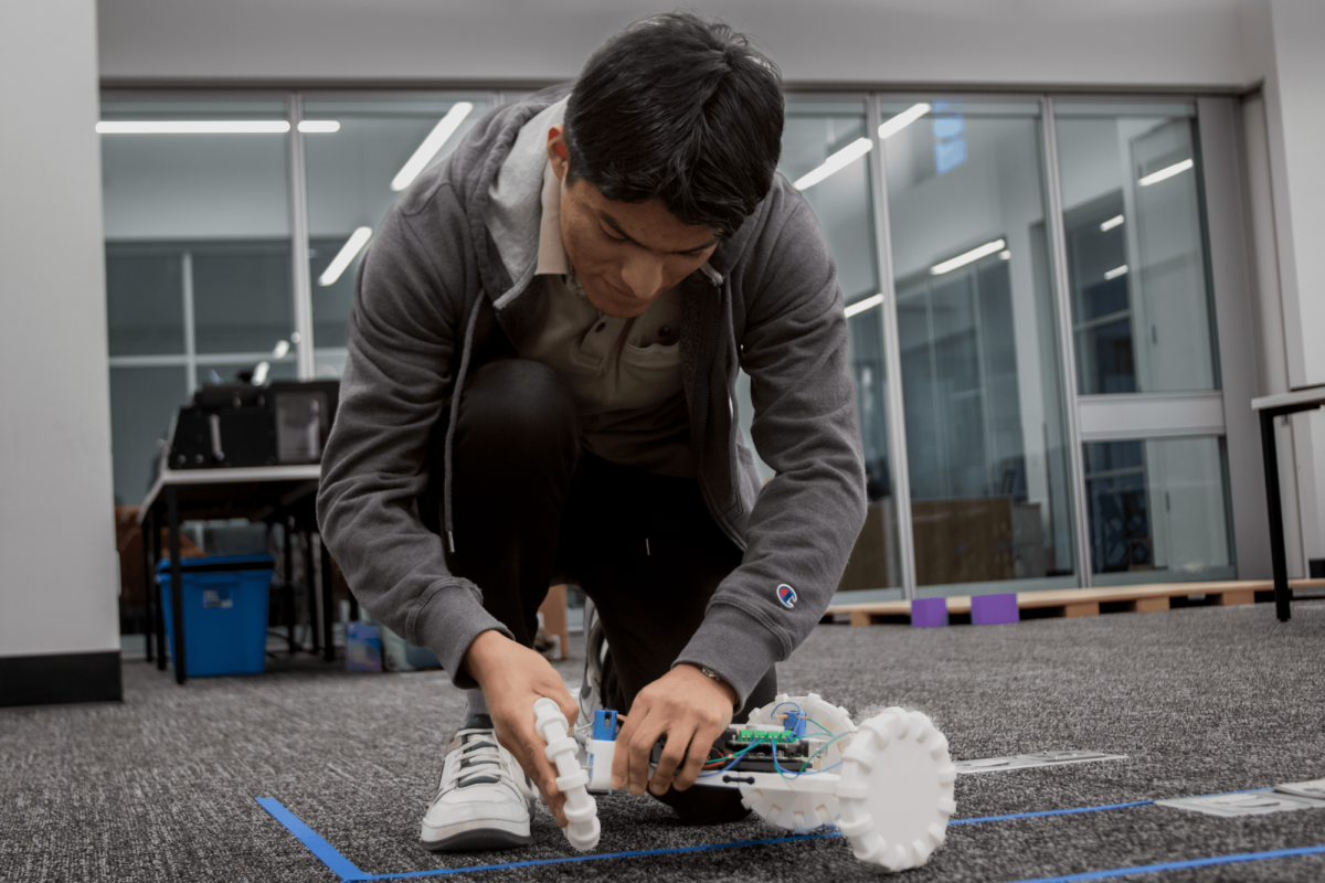 Rodrigo Morales reattaches a wheel to a scale model device.