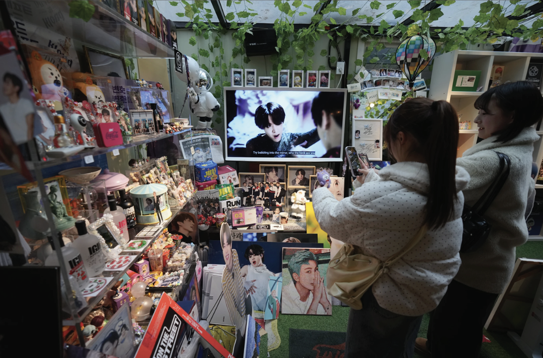 Fans of K-pop band BTS stand look at photos of BTS members at a cafe in Seoul, South Korea.