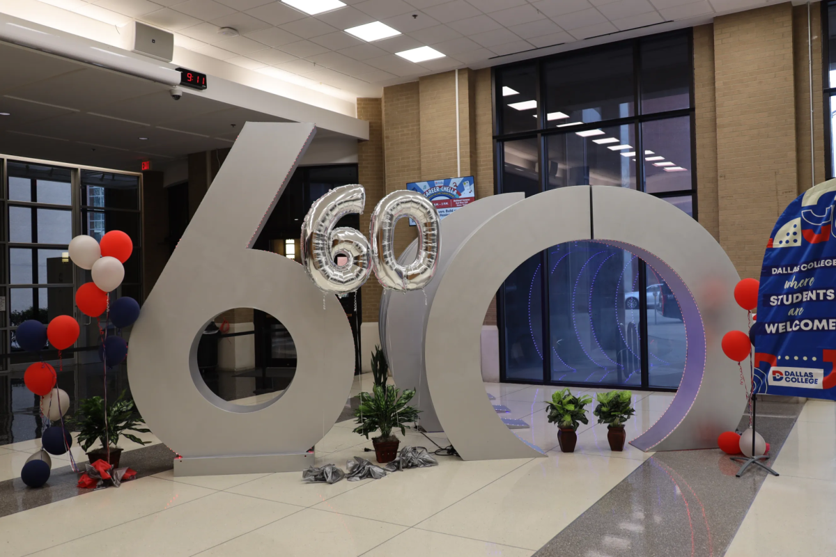 A silver 60th sign is on display on the El Centro campus alongside black, red and white balloons.